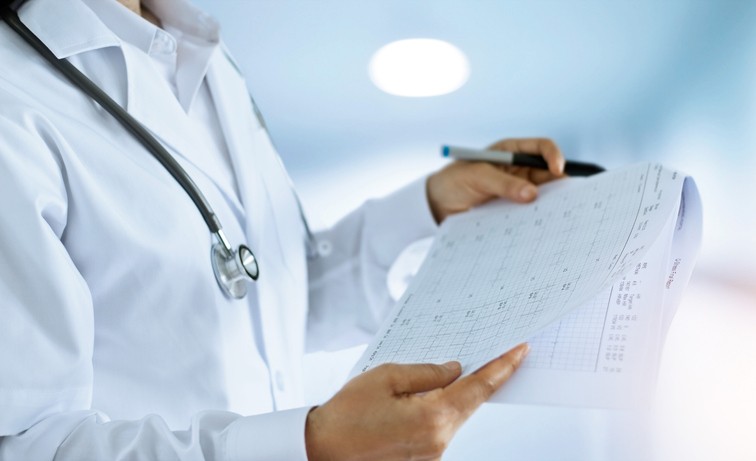 Woman doctor checking and reading final reports in working room of a hospital background